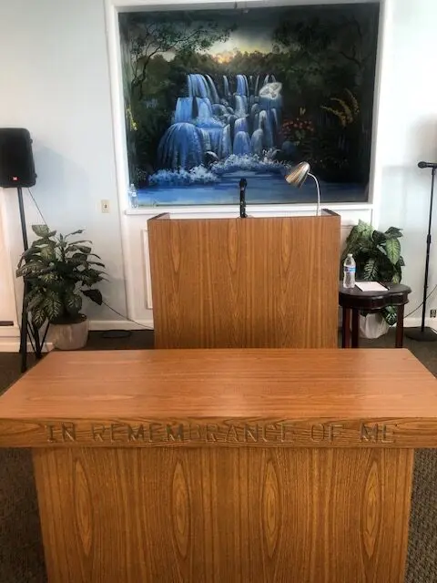 A wooden desk with a painting on the wall behind it.